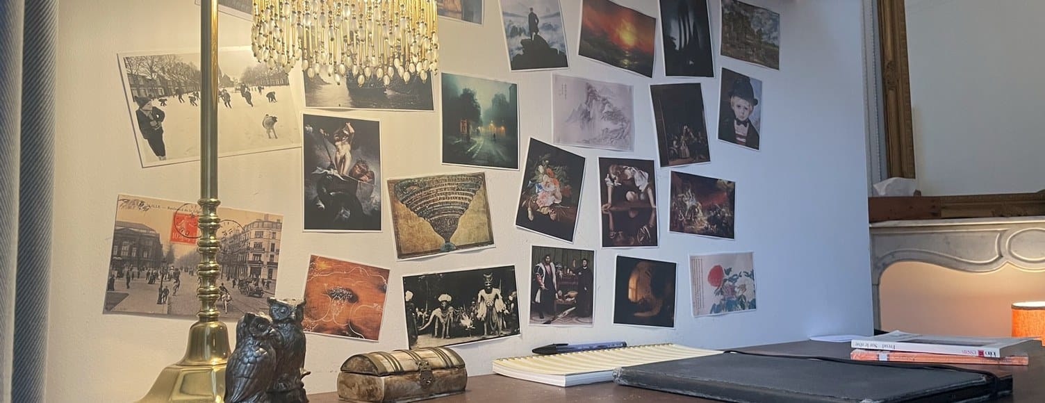 Le bureau, avec sa lampe en laiton, les cartes postales au mur et la cheminée