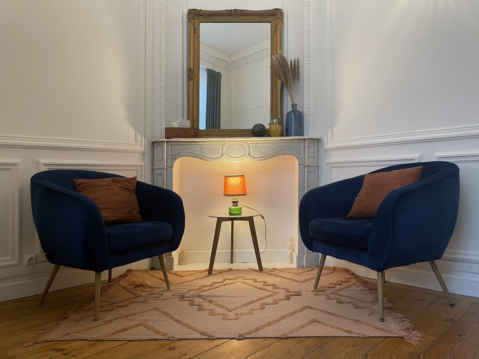 Cabinet : deux fauteuils bleus face à face devant la cheminée, avec une lampe allumée
